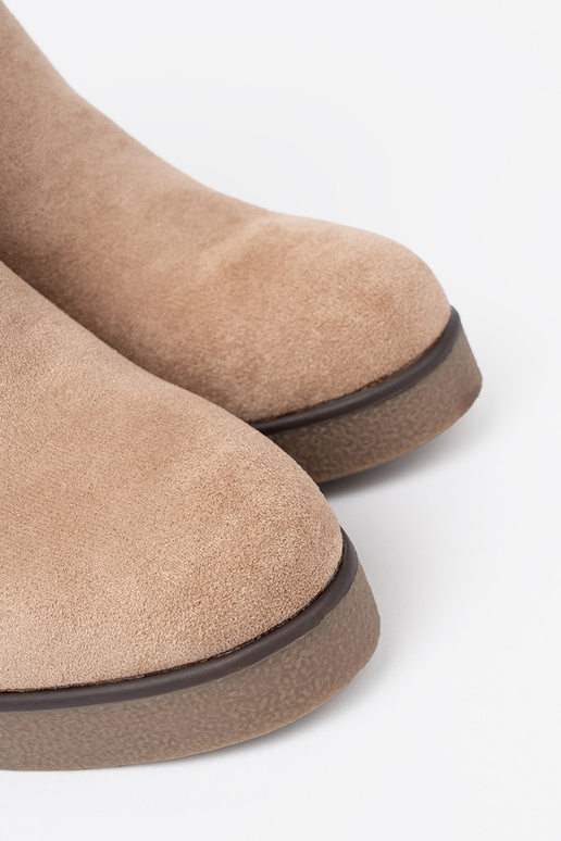 beige boots on a Inedge Inith a decorative buckle